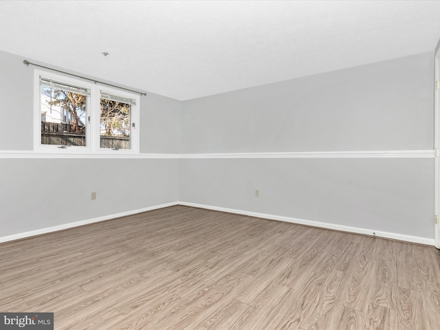 empty room with wood finished floors, baseboards, and a textured ceiling