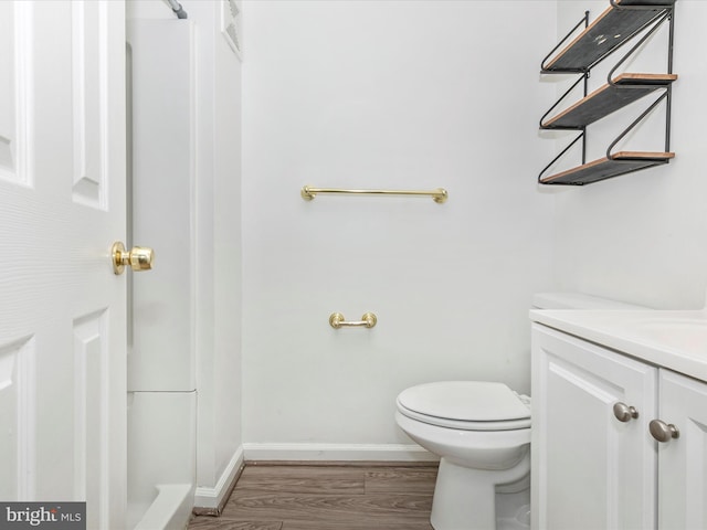 bathroom featuring baseboards, toilet, wood finished floors, and vanity