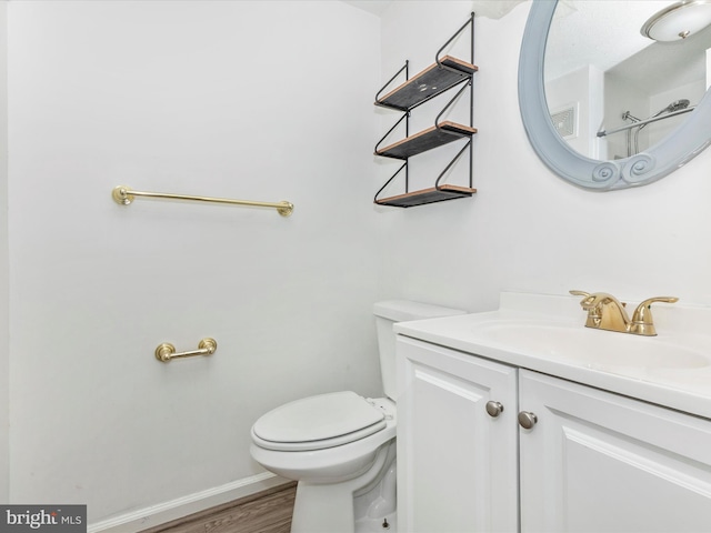 bathroom with vanity, toilet, wood finished floors, and baseboards