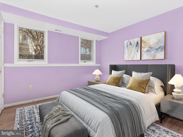 bedroom featuring visible vents, baseboards, and wood finished floors