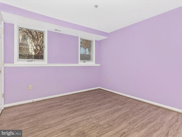 unfurnished room featuring visible vents, baseboards, and wood finished floors