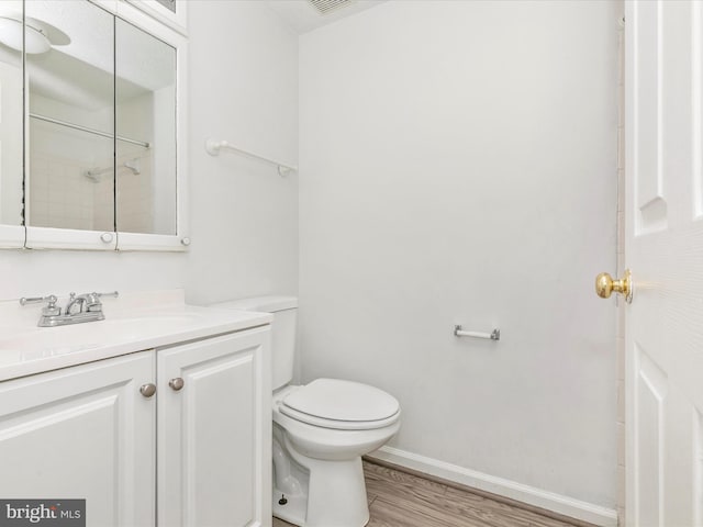 bathroom featuring vanity, toilet, wood finished floors, and baseboards