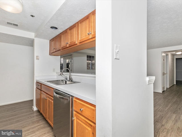 kitchen featuring visible vents, a sink, light countertops, dishwasher, and light wood-type flooring