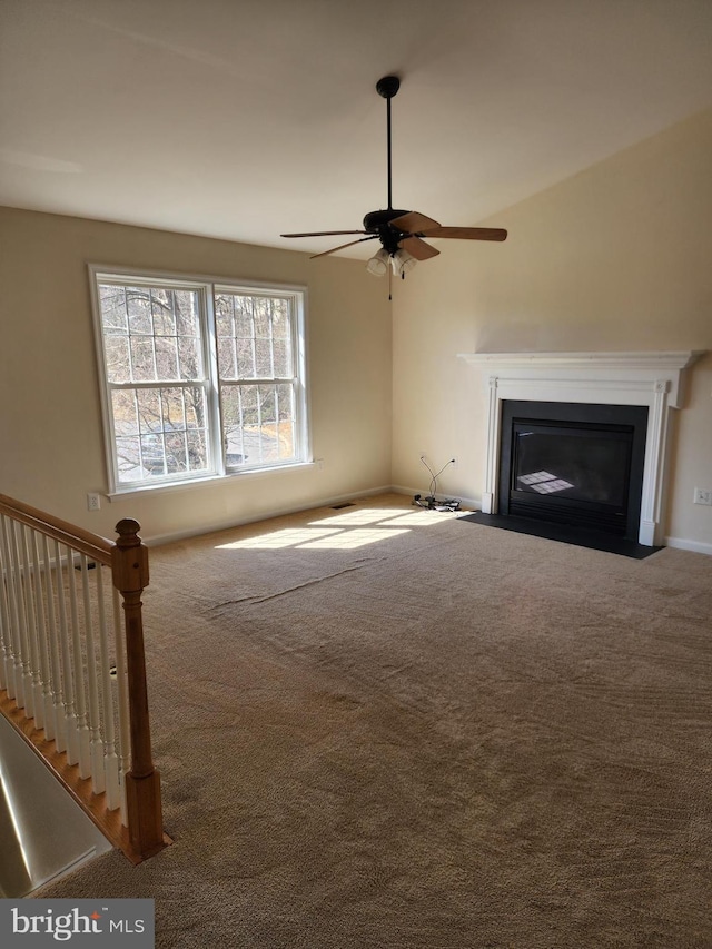 unfurnished living room featuring a fireplace with flush hearth, a ceiling fan, and carpet floors