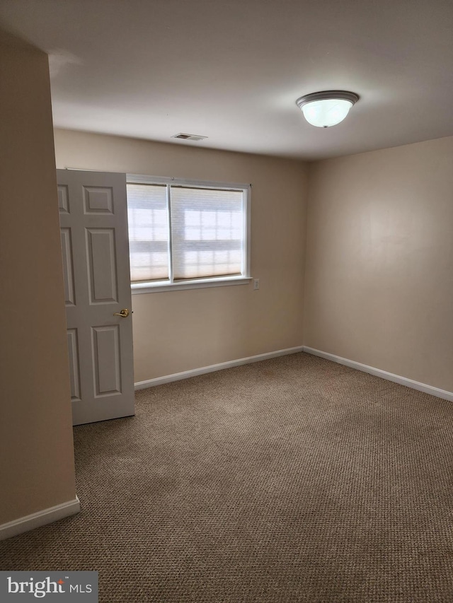 empty room with carpet flooring, visible vents, and baseboards