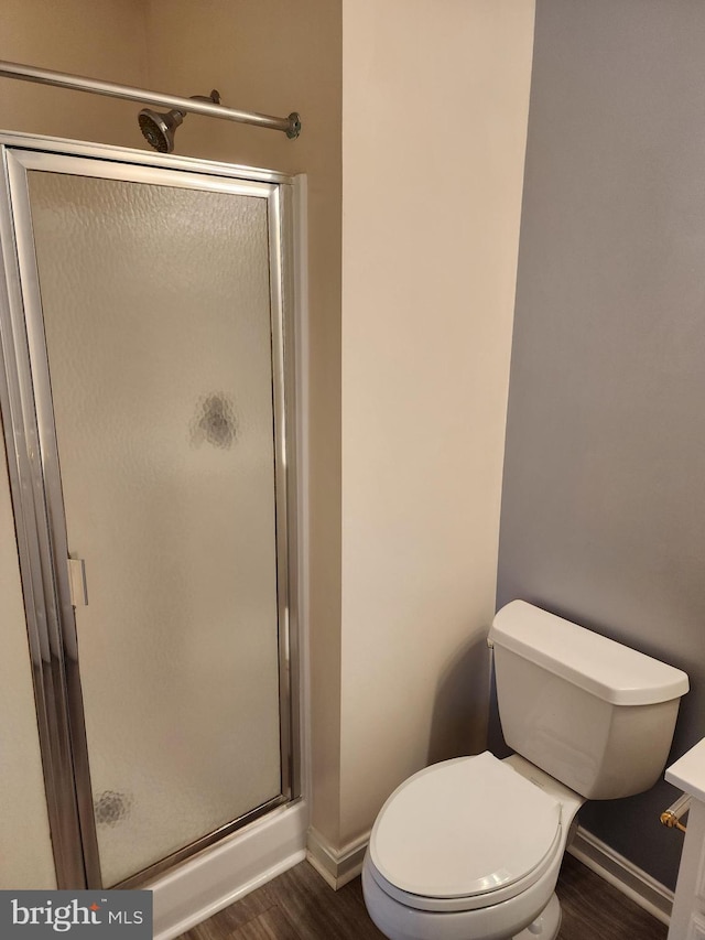 bathroom featuring baseboards, toilet, wood finished floors, and a shower stall