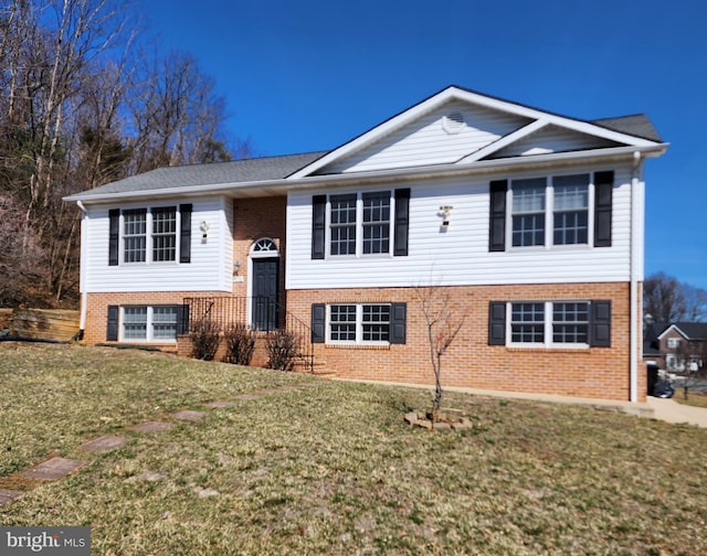 raised ranch with a front lawn and brick siding