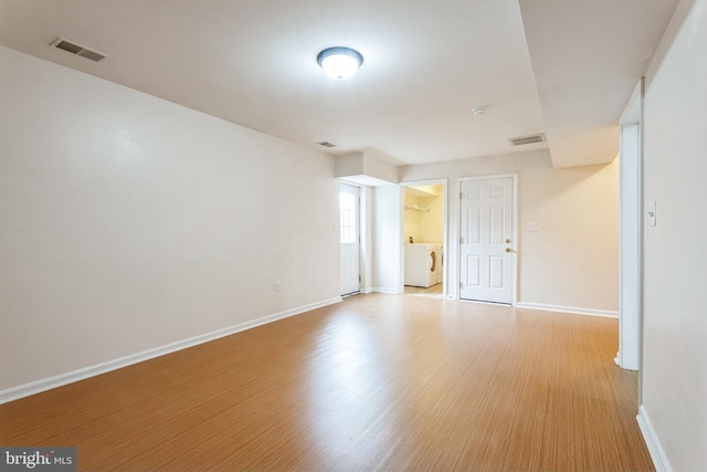 unfurnished room featuring washer and dryer, wood finished floors, visible vents, and baseboards