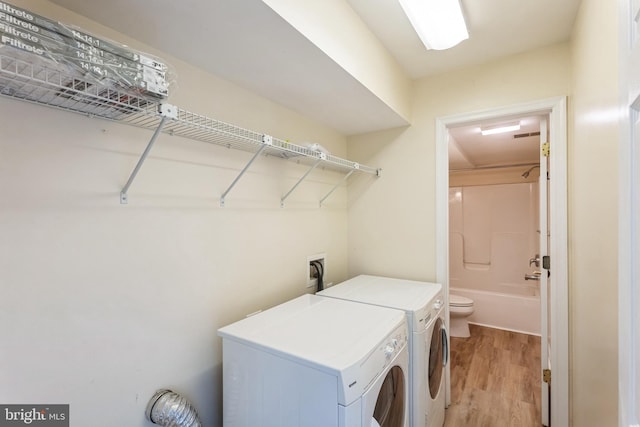 clothes washing area featuring laundry area, washer and dryer, and light wood-type flooring