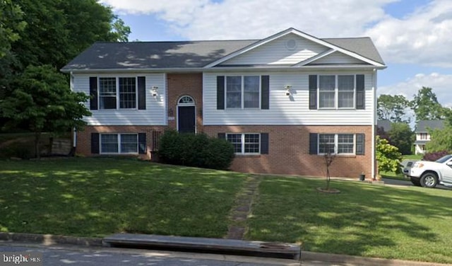 raised ranch featuring brick siding and a front lawn
