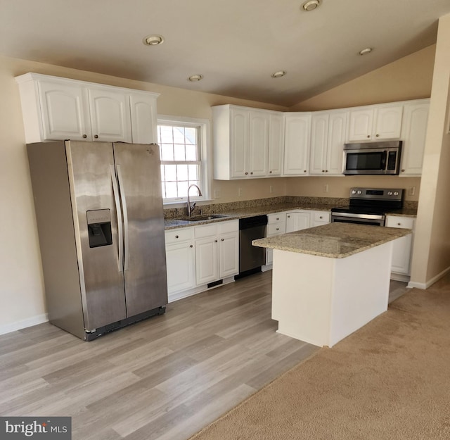 kitchen featuring lofted ceiling, stone countertops, a sink, appliances with stainless steel finishes, and white cabinetry