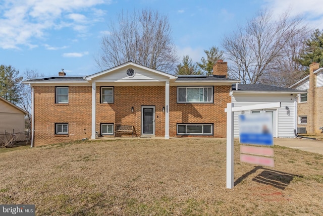 view of front of house with brick siding, solar panels, a chimney, and a front lawn