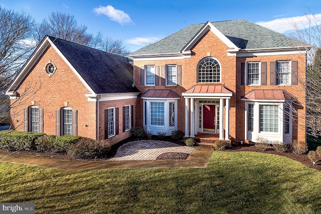 view of front of property with brick siding, a shingled roof, metal roof, a standing seam roof, and a front yard