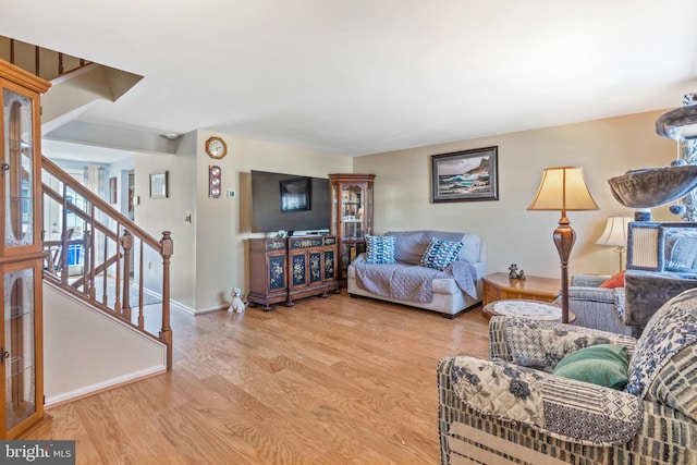 living area featuring stairway, baseboards, and wood finished floors