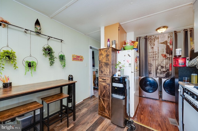 kitchen featuring a barn door, range, wood finished floors, freestanding refrigerator, and washer and dryer