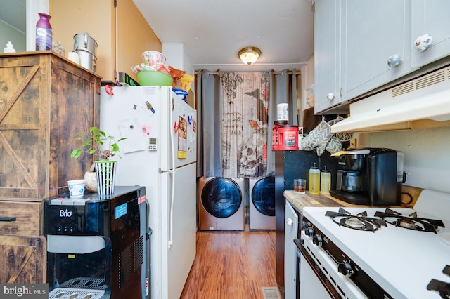 kitchen with light wood-type flooring, white appliances, washer and clothes dryer, and light countertops