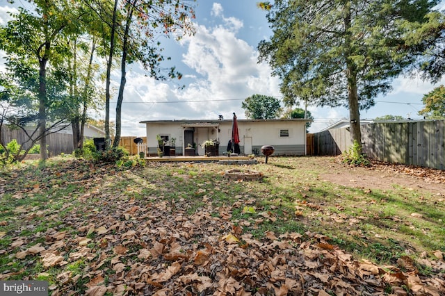 rear view of property featuring an outdoor fire pit, a fenced backyard, and a wooden deck