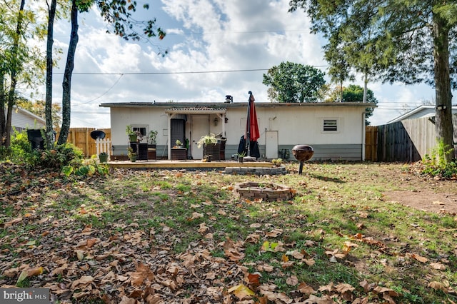 rear view of house with a fire pit, fence, and a wooden deck