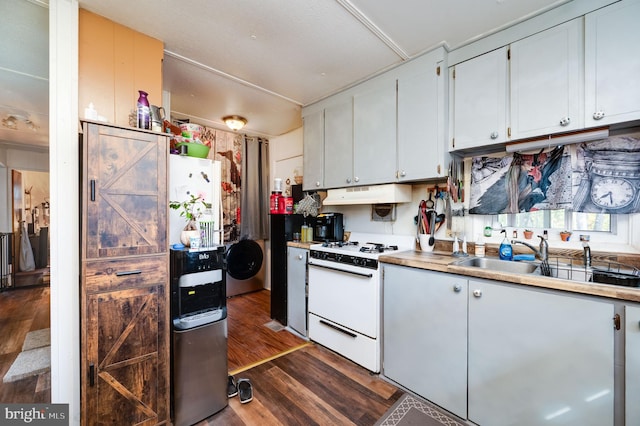 kitchen with dark wood finished floors, light countertops, white gas stove, under cabinet range hood, and a sink