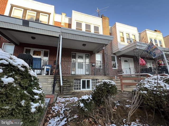 view of property featuring a porch and brick siding