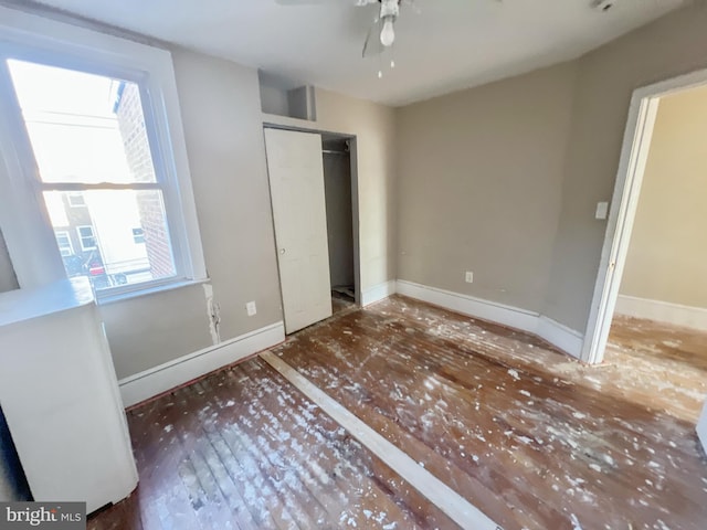 unfurnished bedroom with a closet, wood finished floors, and baseboards