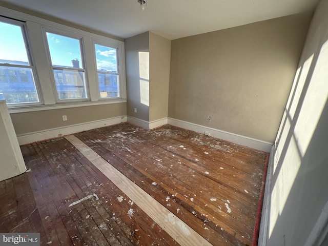 empty room featuring baseboards and hardwood / wood-style flooring