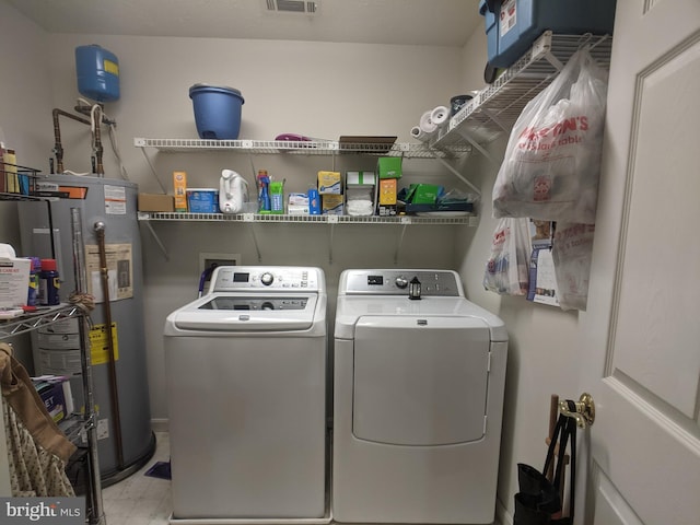 laundry room with visible vents, laundry area, water heater, and washer and clothes dryer