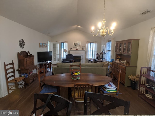 dining space featuring a fireplace, visible vents, vaulted ceiling, and wood finished floors