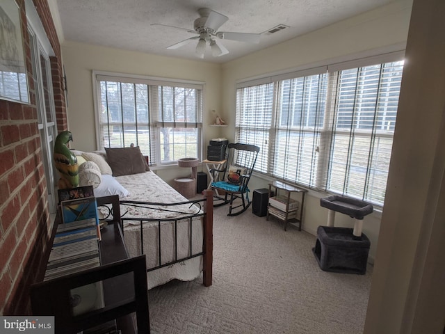 bedroom with a ceiling fan, visible vents, a textured ceiling, and carpet flooring