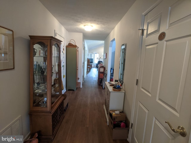 hallway with a textured ceiling, visible vents, and dark wood-style flooring