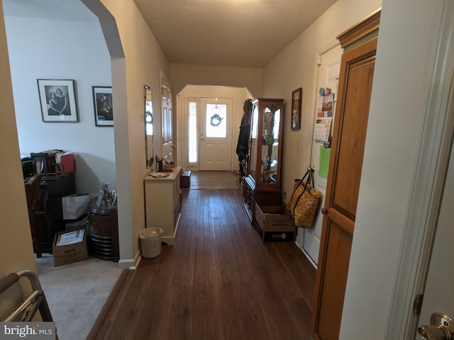 interior space with arched walkways, dark wood finished floors, and baseboards