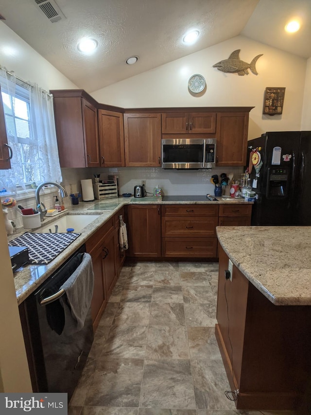 kitchen featuring light stone countertops, black appliances, vaulted ceiling, and a sink