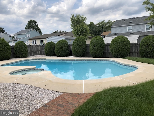 view of swimming pool featuring a residential view, a pool with connected hot tub, and a fenced backyard