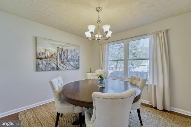 dining room with a notable chandelier, baseboards, and a textured ceiling