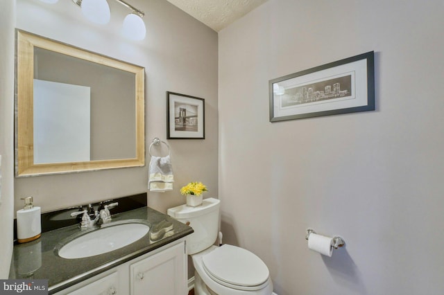 bathroom featuring a textured ceiling, toilet, and vanity