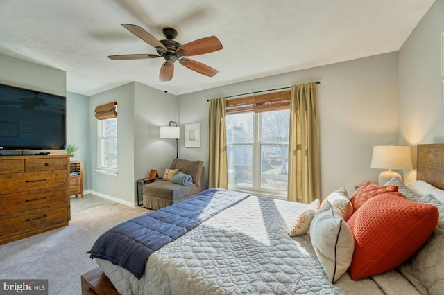 carpeted bedroom with multiple windows, a textured ceiling, baseboards, and ceiling fan