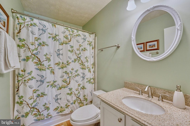 bathroom with a textured ceiling, shower / bath combo, vanity, and toilet