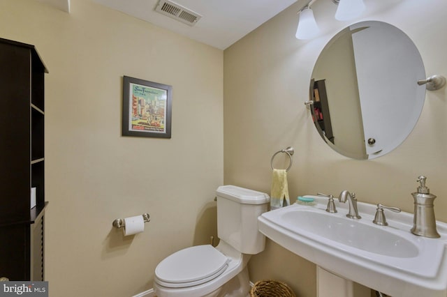 bathroom featuring visible vents, toilet, and a sink