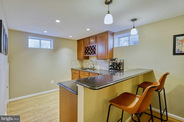 kitchen with a sink, tasteful backsplash, a healthy amount of sunlight, and a peninsula