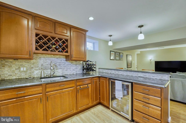 kitchen featuring brown cabinets, a sink, dark stone counters, wine cooler, and a peninsula