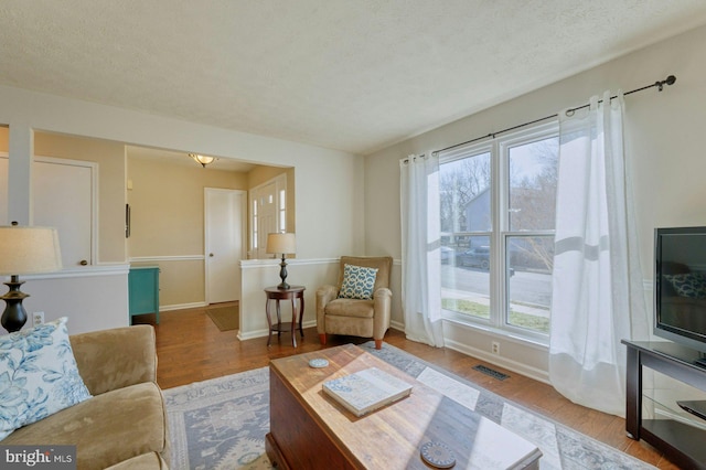 living room featuring wood finished floors, baseboards, and a healthy amount of sunlight