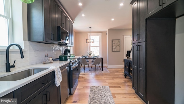 kitchen featuring light wood-style flooring, a sink, stainless steel appliances, light countertops, and backsplash