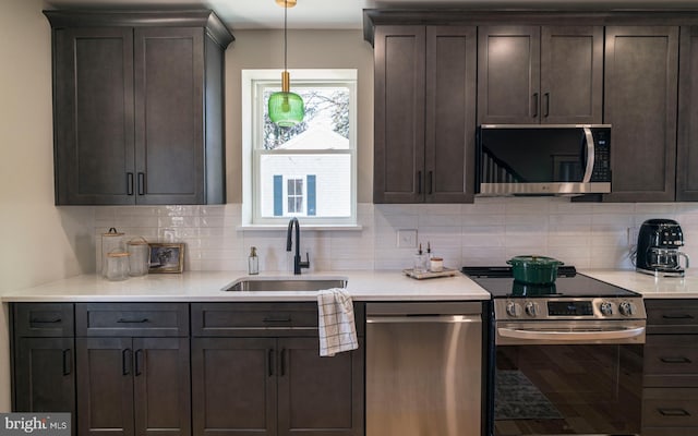 kitchen featuring appliances with stainless steel finishes, a sink, dark brown cabinets, and tasteful backsplash