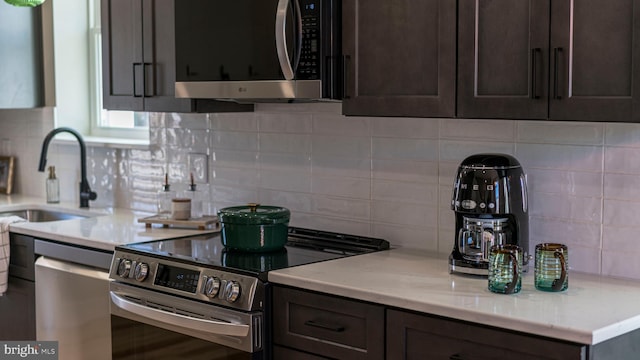 kitchen with stainless steel appliances, backsplash, a sink, and dark brown cabinetry