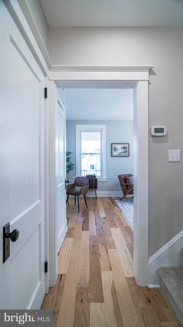 hallway featuring stairs, light wood-style flooring, and baseboards