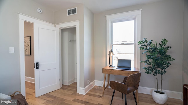 home office with light wood-style floors, visible vents, and baseboards