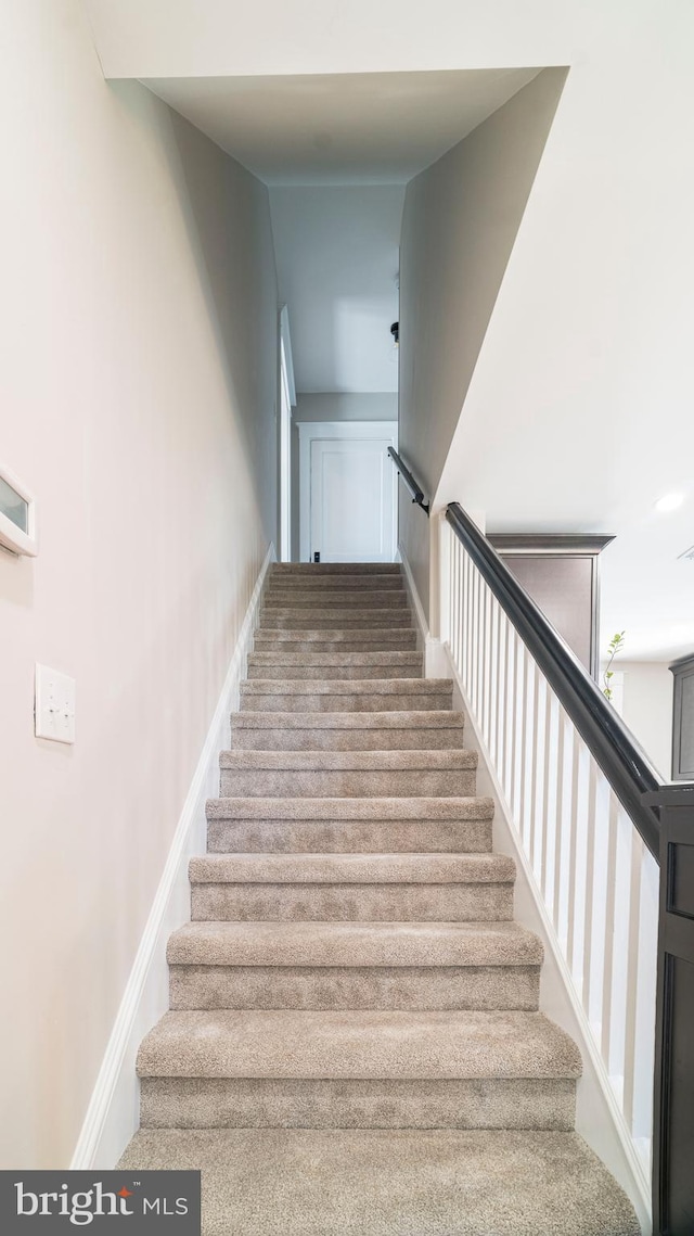 staircase featuring carpet floors and baseboards