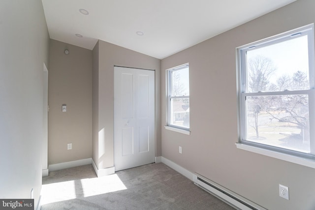 unfurnished bedroom with a baseboard radiator, light colored carpet, baseboards, vaulted ceiling, and a closet