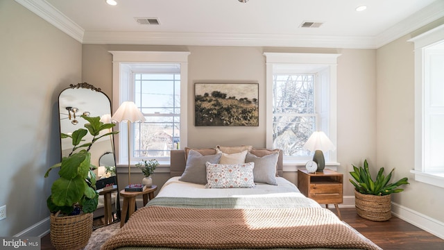 bedroom featuring baseboards, crown molding, visible vents, and wood finished floors