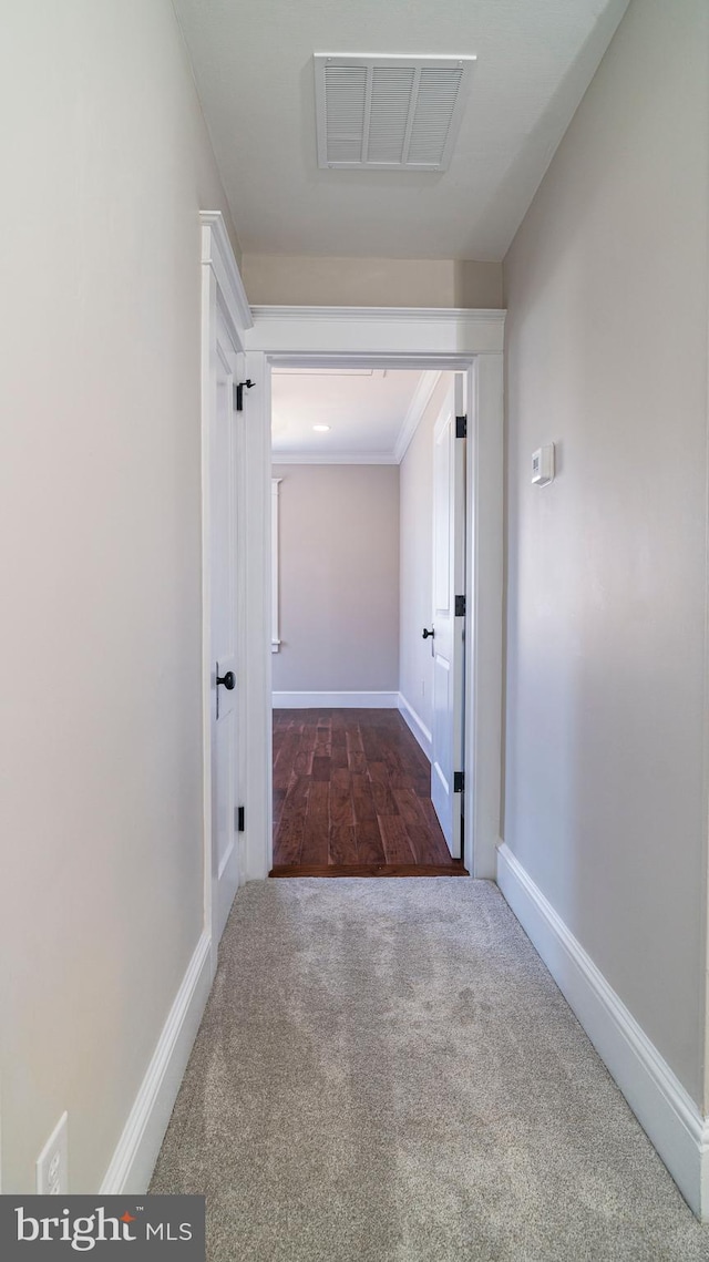 corridor with carpet floors, baseboards, and visible vents